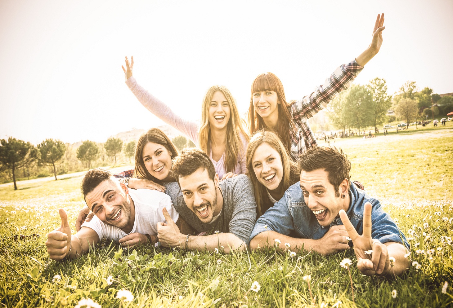 Friends group having fun together with self portrait on grass meadow – Friendship youth concept with young happy people at picnic camping outdoor – Warm vintage filter with backlight contrast sunshine