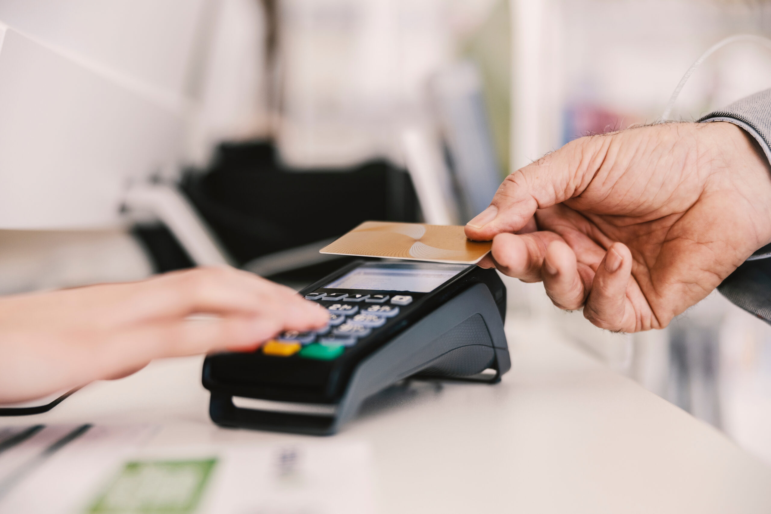 Close up of hand with credit card paying bill on pos terminal.