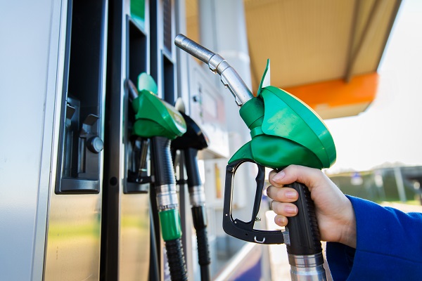 close up of hand holding hose at gas station