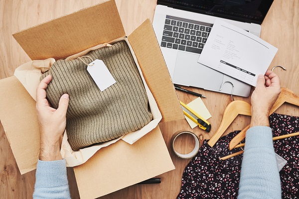 Business owner packing online order to delivery to customer. Preparing parcel box with clothes product from online shop