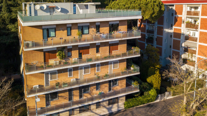 Vista aerea di un palazzo giallo in una giornata nuvolosa. Tanti sono i balconi e le finestre in questo numeroso condominio.